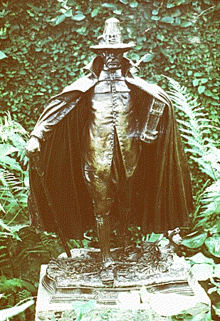 Puritan statue stands grimly posed in a cemetary (unseen)